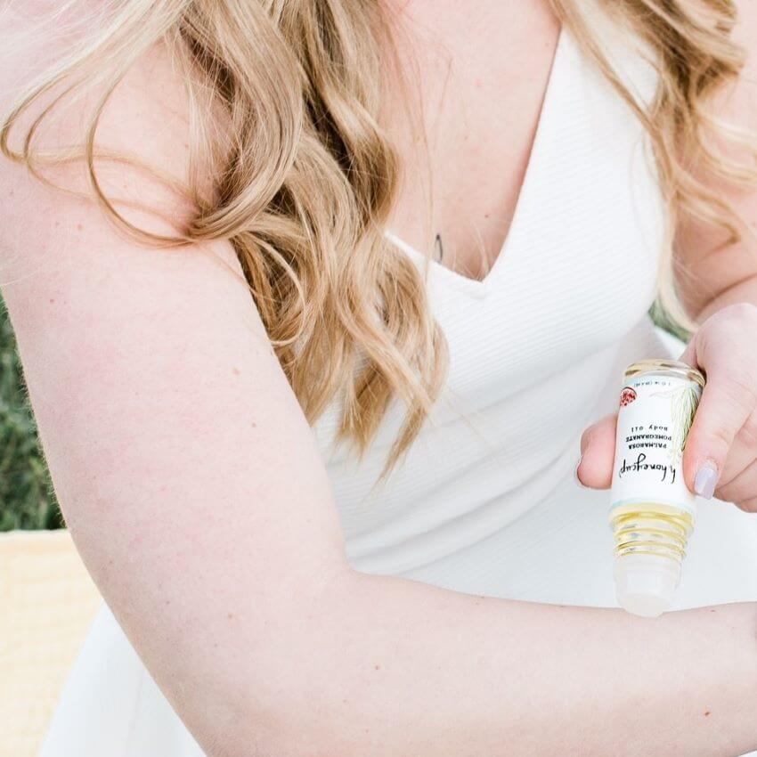 Woman with blond hair, white top, applying body oil for blog: DISCOVER THE BLISS OF NATURAL BODY CARE: EMBRACE SELF-LOVE AND RADIANT SKIN