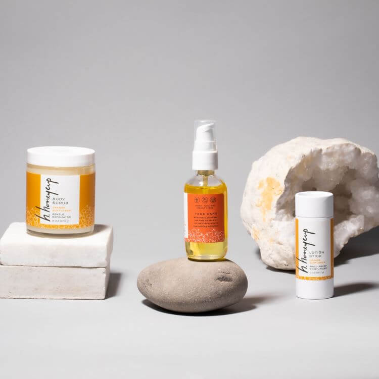 Stylized image of H. Honeycup full size products including body scrub, body oil, and lotion stick. For blog discussing rebranding process for this natural skincare brand