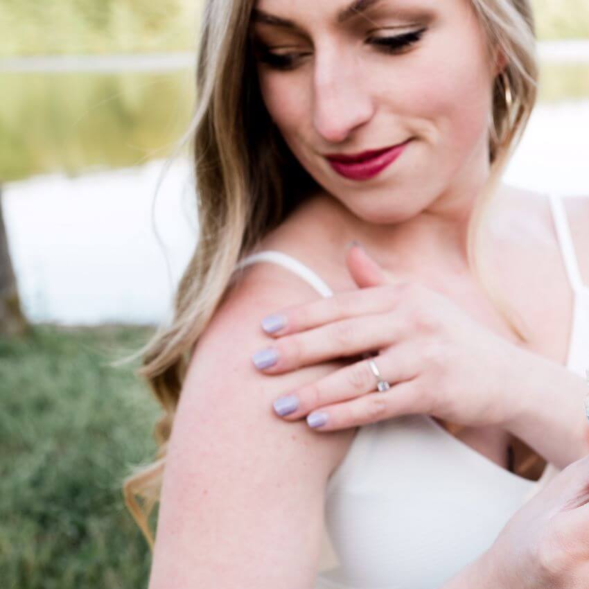 Woman looking at her shoulder applying lotion outdoors for blog: TRANSFORM YOUR BODY CARE ROUTINE WITH CLEAN BEAUTY PRODUCTS