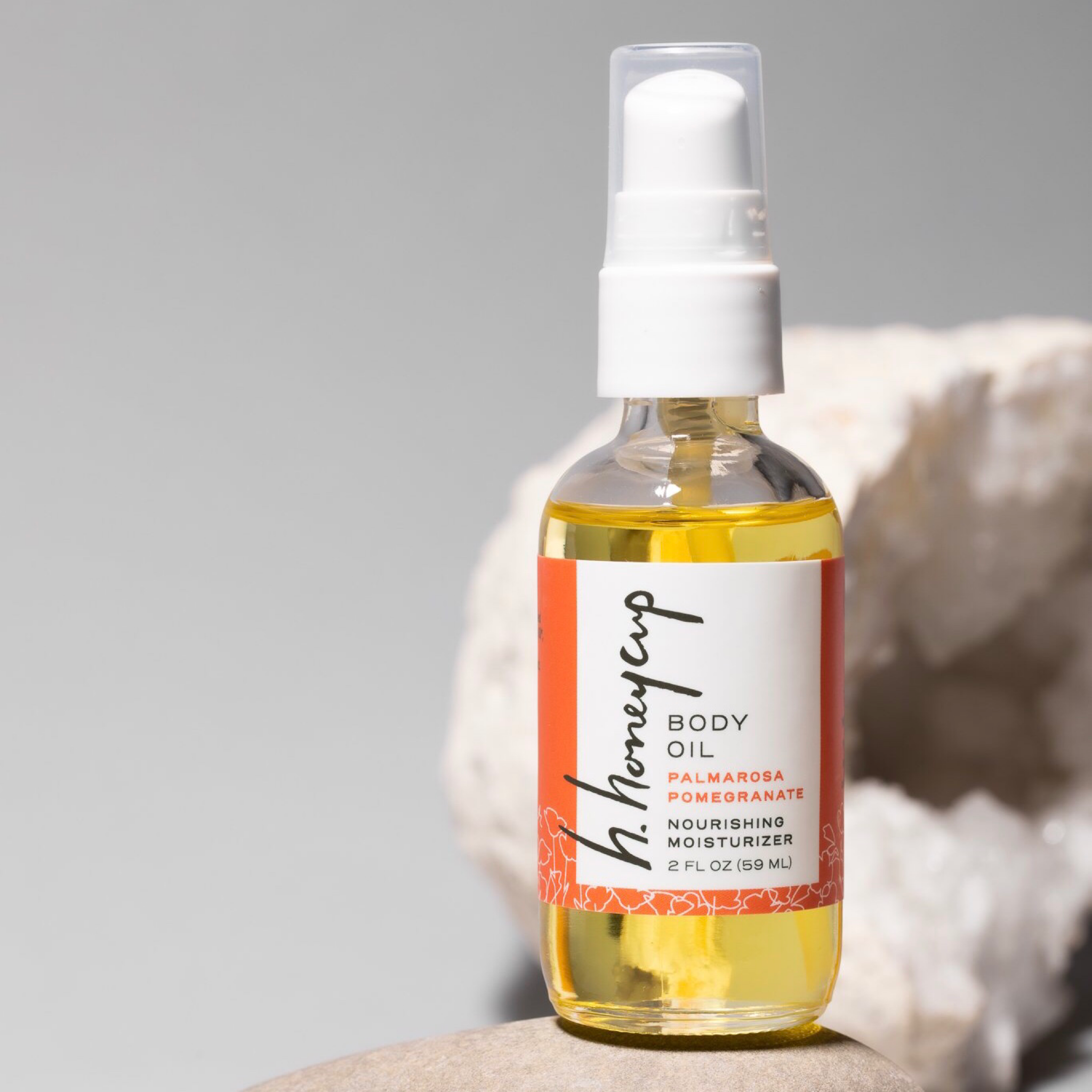 Natural body oil with palmarosa and lavender essential oils in 2 oz recyclable clear glass bottle with white spray top